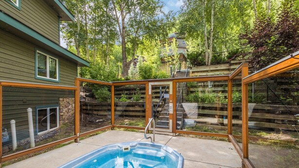 A backyard with a swimming pool, wooden deck, and a stone wall. - Riverside Condo with Mountain and Town views and updated furnishings. (Telluride)