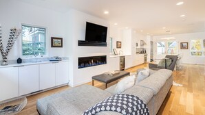 Ein modernes Wohnzimmer mit Kamin, einer Couch und einem Fernseher.