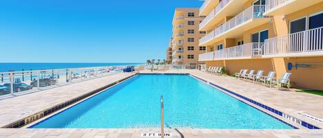 A swimming pool with a 3 ft 8 in depth marker, surrounded by a tiled deck and a building with balconies overlooking the pool.