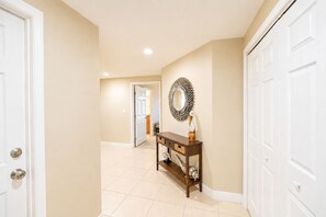 A hallway with beige walls, white doors, a wooden console table with baskets, and a decorative mirror.