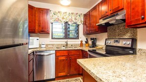 A kitchen with wooden cabinets, stainless steel appliances, and a granite countertop. - Island Touches w/Modern Kitchen, Wood Floors, Lanai, Flat Screen, WiFi–Kaha Lani 203 (LIHUE)