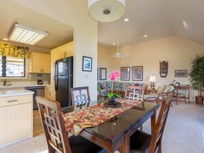 A modern kitchen with wooden cabinets, a black refrigerator, and a dining area with a glass table and chairs.