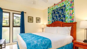 A bedroom with a bed, a nightstand, a window with curtains, and a ceiling fan.