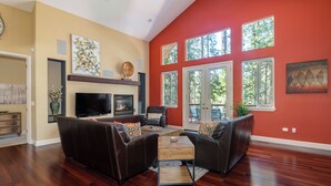 A spacious living room with a large flat-screen TV, a fireplace, and a comfortable seating area with leather sofas and a coffee table. - Sierra Sky - Luxurious Retreat with Free Private Lake Access! (Arnold)