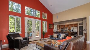 A spacious living room with a large brown leather sofa, a coffee table, and a red accent wall. - Sierra Sky - Luxurious Retreat with Free Private Lake Access! (Arnold)