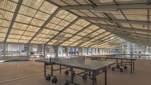 A spacious indoor area with a high ceiling, large windows, and multiple ping pong tables. - Las Palmas Resort #1018 | All-Inclusive Amenities (Saint George)