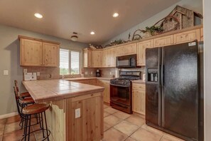 A kitchen with wooden cabinets, a stainless steel refrigerator, a microwave, and a stove. - Las Palmas Resort #1018 | All-Inclusive Amenities (Saint George)