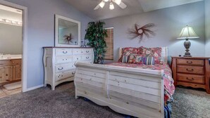 A bedroom with a bed, dresser, nightstand, lamp, mirror, and ceiling fan. - Las Palmas Resort #1018 | All-Inclusive Amenities (Saint George)