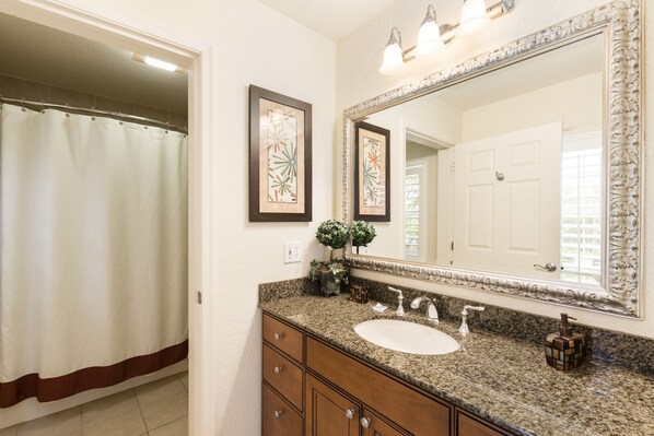 A bathroom with a sink, mirror, and shower curtain.