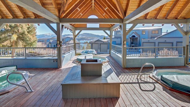 A covered outdoor deck with a hot tub, seating, and a view of a mountain range. - Two Bedroom Plus Loft with Awesome Views of Lake Dillon (Frisco)