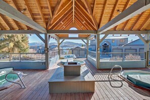 A covered outdoor deck with a hot tub, seating, and a view of a mountain range. - Two Bedroom Plus Loft with Awesome Views of Lake Dillon (Frisco)
