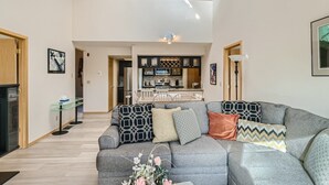 A spacious living area with a grey sofa, a dining table, and a kitchen in the background. - Two Bedroom Plus Loft with Awesome Views of Lake Dillon (Frisco)