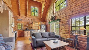Ein rustikaler Innenraum einer Blockhütte mit Wohnzimmer, Küche und Essbereich.