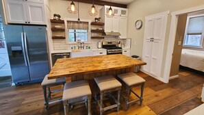A kitchen with a large wooden island, white cabinets, stainless steel appliances, and pendant lighting. - HotTub, OutdoorShower, Renovated Barndominium, WiFi, Fireplace, Pet Friendly (Ferguson)