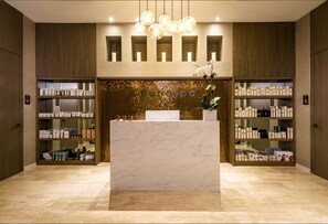 A spa reception area with a marble counter, shelves of spa products, and a mosaic wall.