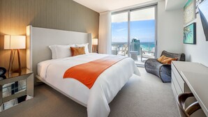 A hotel room with a large bed, a desk, a chair, and a view of the city and ocean. - BeachFront @Hyde GreatOceanView 2BR Suite (Hollywood)