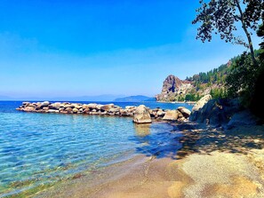Une vue dégagée sur la côte, avec un rivage rocheux, une eau calme et une formation rocheuse remarquable.