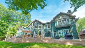 A large, two-story house with a deck and outdoor seating area. - Luxury Lakefront Gem w/ Hot Tub & Serenity (Oakland)