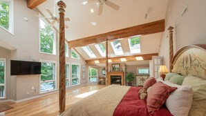 A spacious bedroom with a large bed, skylights, a fireplace, and a television. - Luxury Lakefront Gem w/ Hot Tub & Serenity (Oakland)