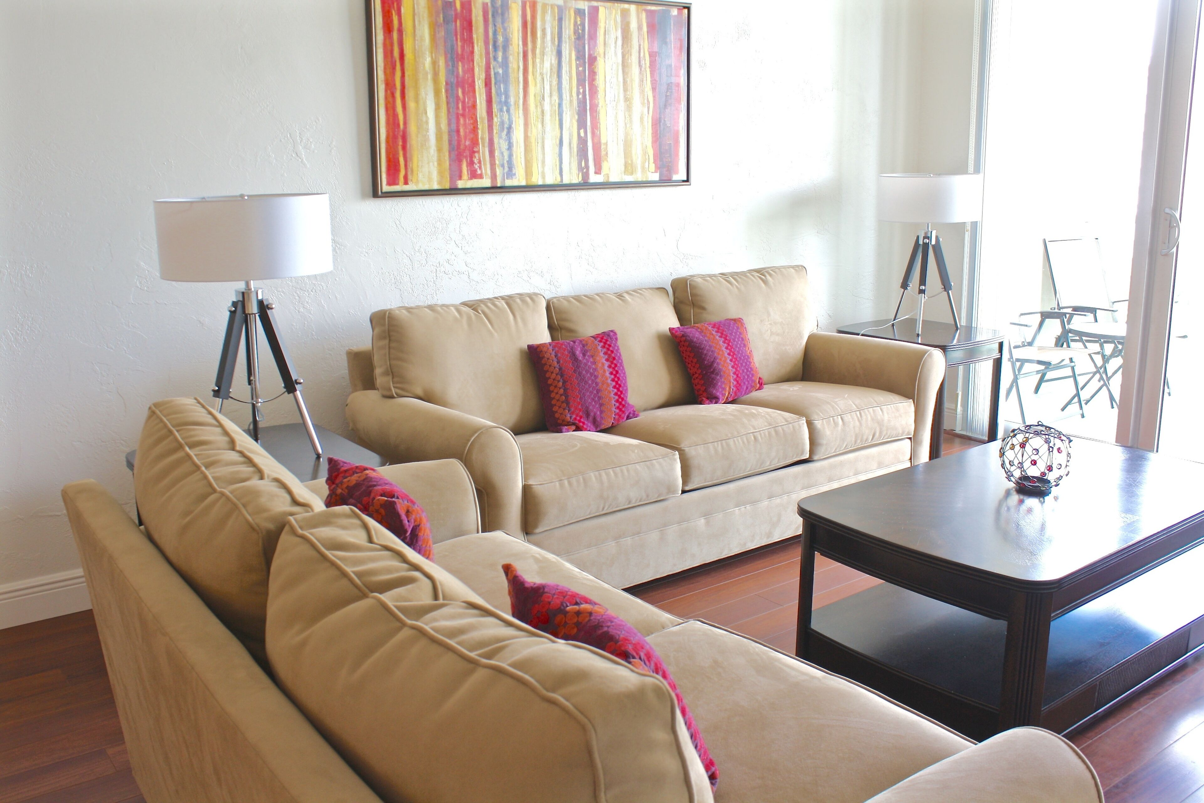 A living room with a beige sofa set, a coffee table, and a lamp.