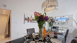 Un comedor con una mesa dispuesta para dos personas, que incluye un florero, copas de vino y una jarra.