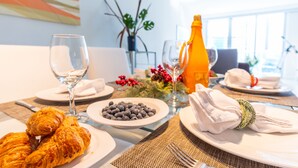 Een ontbijttafel met croissants, bosbessen, wijnglazen en een fles sinaasappelsap.
