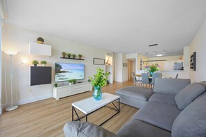 A modern living room with a grey sofa, a flat-screen TV, and a coffee table with a vase.