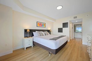 A modern bedroom with a large bed, a nightstand, a wall-mounted lamp, and a ceiling light. - Spacious condo w/ terrace overlooking the bay | WIFI + Parking (Sunny Isles Beach)