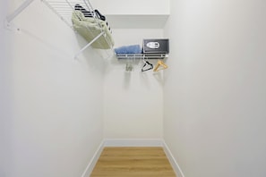 A narrow hallway with a wooden floor, a metal rack with shoes, and a black object on the wall. - Spacious condo w/ terrace overlooking the bay | WIFI + Parking (Sunny Isles Beach)