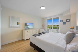 A hotel room with a bed, a television, a dresser, a chair, and a balcony with a view.