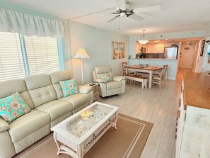A living room with a sofa, chairs, a coffee table, and a dining area with a table and chairs.