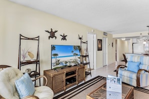 A living room with a television, wicker furniture, and wall decorations.