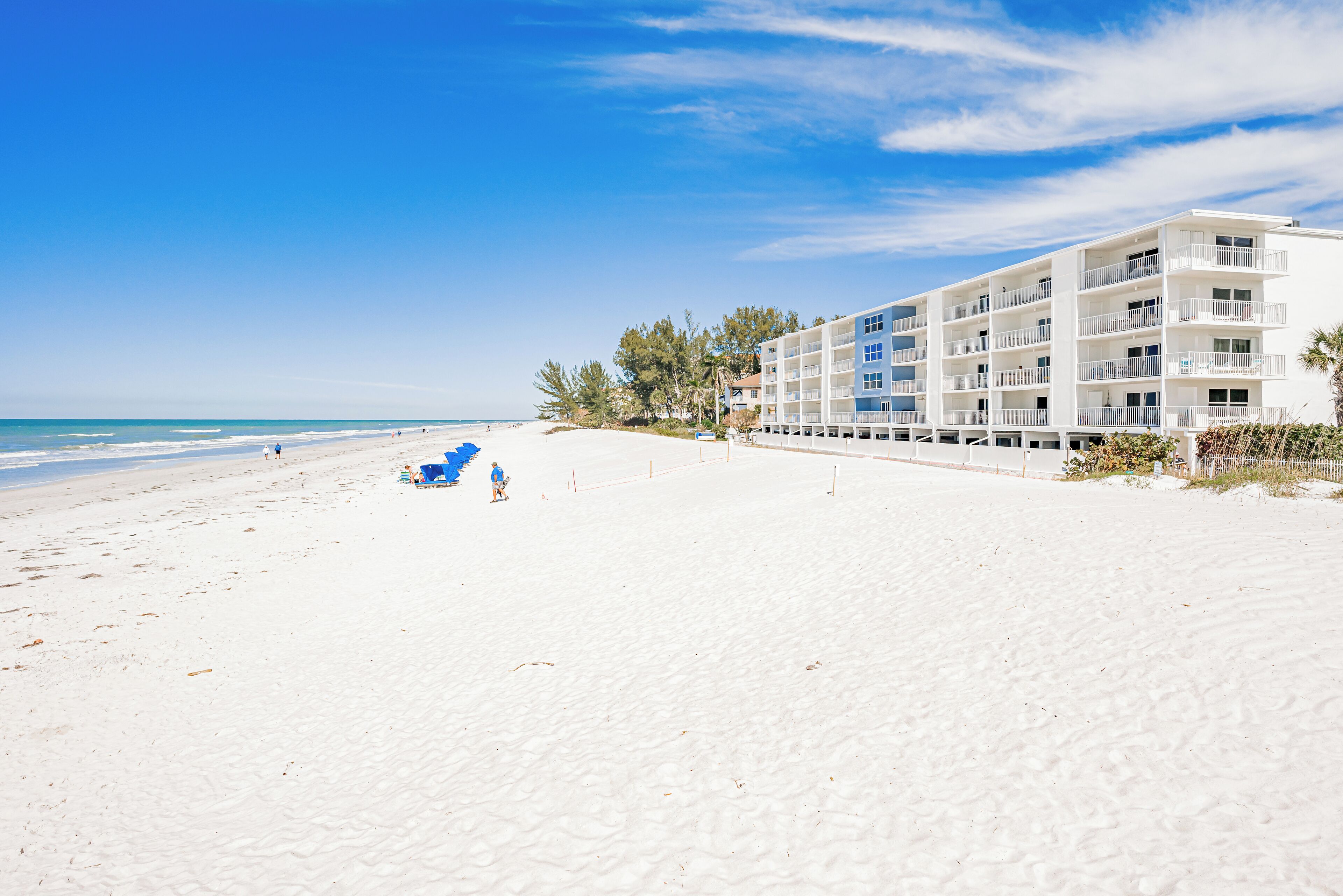 A beachfront hotel with multiple balconies, a sandy beach, and ocean views.
