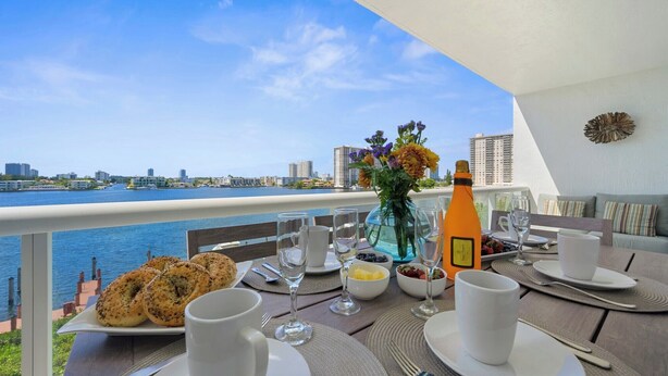 A table set for breakfast with a view of the water and city skyline. - Comfortable condo with amazing bay views | WIFI + Parking (Sunny Isles Beach)