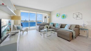 A modern living room with a sofa, coffee table, and a view of the sea through large windows. - Comfortable condo with amazing bay views | WIFI + Parking (Sunny Isles Beach)