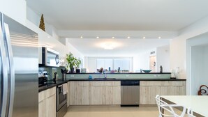 Una cucina moderna con elettrodomestici in acciaio inossidabile, un'isola centrale e un'area pranzo con sedie bianche.