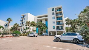 A multi-story building with balconies, a parking lot, and palm trees. - Quiet Waters C1 - INTERCOASTAL VIEW Condo! (Indian Shores)
