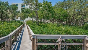 A wooden boardwalk leading to a building surrounded by lush greenery. - Quiet Waters C1 - INTERCOASTAL VIEW Condo! (Indian Shores)