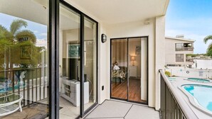A balcony with a pool, a glass door leading to a bedroom, and a view of the sea. - Quiet Waters C1 - INTERCOASTAL VIEW Condo! (Indian Shores)