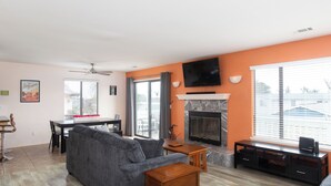 Una sala de estar con chimenea, televisor montado en la pared y comedor con mesa y sillas.