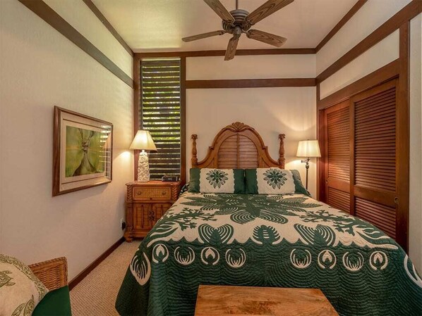 A bedroom with a large bed, wooden headboard, and a ceiling fan. There is a nightstand with lamps and a framed picture on the wall. - Tropical Ground Floor Suite w/Lanai, Kitchen Ease, WiFi–Kiahuna Plantation #2070 (KOLOA)