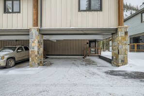 A building with a covered entrance, stone pillars, and a vehicle parked outside.