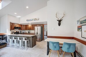 Une cuisine moderne avec des meubles en bois, des appareils électroménagers en acier inoxydable et un îlot central doté de tabourets de bar.