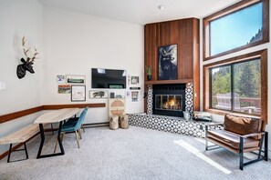 A modern living room with a fireplace, a large window, and a dining area. - 2 Bedroom with Large deck right in the heart of everything!! (Frisco)