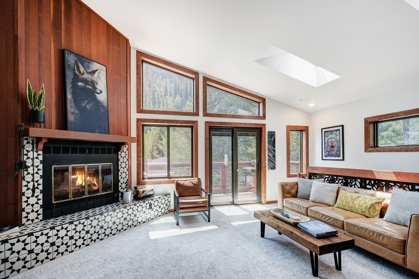 A spacious living room with a fireplace, large windows, and a high ceiling.
