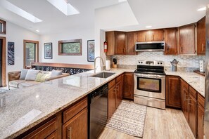 A modern kitchen with granite countertops, stainless steel appliances, and wooden cabinets. - 2 Bedroom with Large deck right in the heart of everything!! (Frisco)
