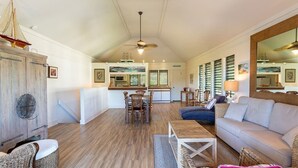 A spacious living area with a dining table, a sofa, and wicker furniture. - Open 2-Level Rental w/Super View, Kitchen Ease, WiFi, Lanai–Kiahuna Plantation #2209 (KOLOA)