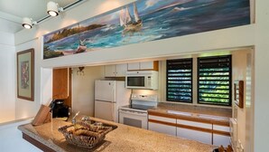 A kitchen with granite countertops, a microwave, a refrigerator, and a large window with blinds. - Open 2-Level Rental w/Super View, Kitchen Ease, WiFi, Lanai  –Kiahuna Plantation #2209 (KOLOA)