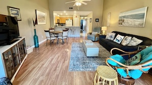 A spacious living room with a sofa, chairs, a dining area, and a kitchen in the background. - Cozy Silver-rated condo, perfect for enjoying beautiful Florida. (Saint Augustine)