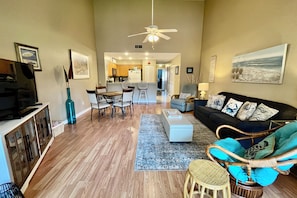 A spacious living room with a sofa, chairs, a dining area, and a kitchen in the background. - Cozy Silver-rated condo, perfect for enjoying beautiful Florida. (Saint Augustine)